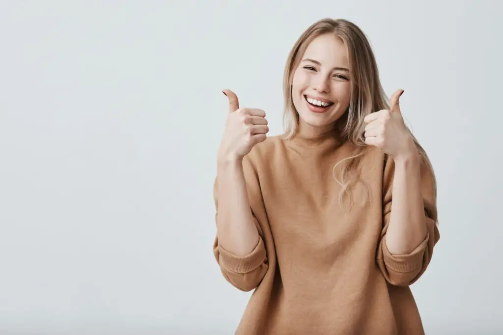 A smiling woman giving two thumbs up - How to Brush Your Teeth with Braces: Technique, Tools, and the Gumline Shadow Zone Limestone Hills Orthodontics Austin TX