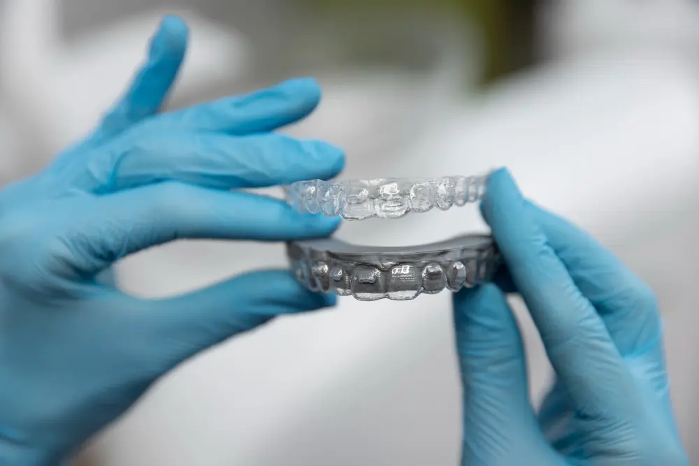 Gloved hands hold clear orthodontic aligners, possibly Invisalign. Limestone Hills Orthodontics in Austin, TX, offers clear teeth straightening solutions.