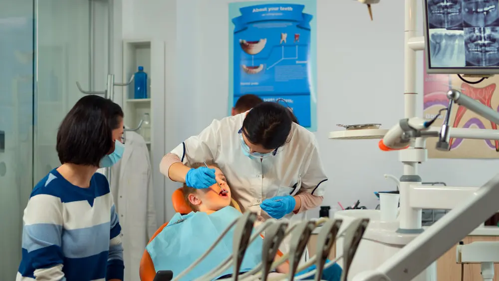A young child, who appears to be of Caucasian descent based on their features, receives dental care while a woman, who may be of Asian descent based on her features, watches. Limestone Hills Orthodontics in Austin, TX.