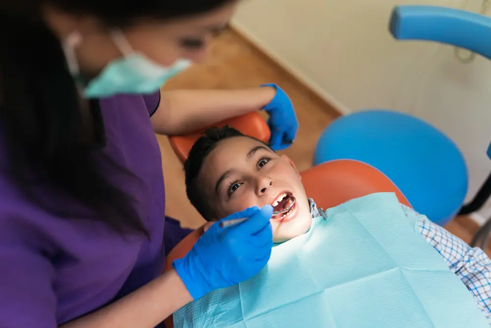 a child sitting in a chair with a dentist in the background