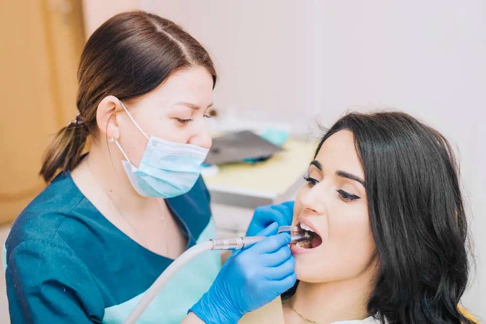 A dental professional, who appears to be a woman and may be of Caucasian descent based on her features, works on a patient's teeth. Limestone Hills Orthodontics in Austin, TX, provides dental services.