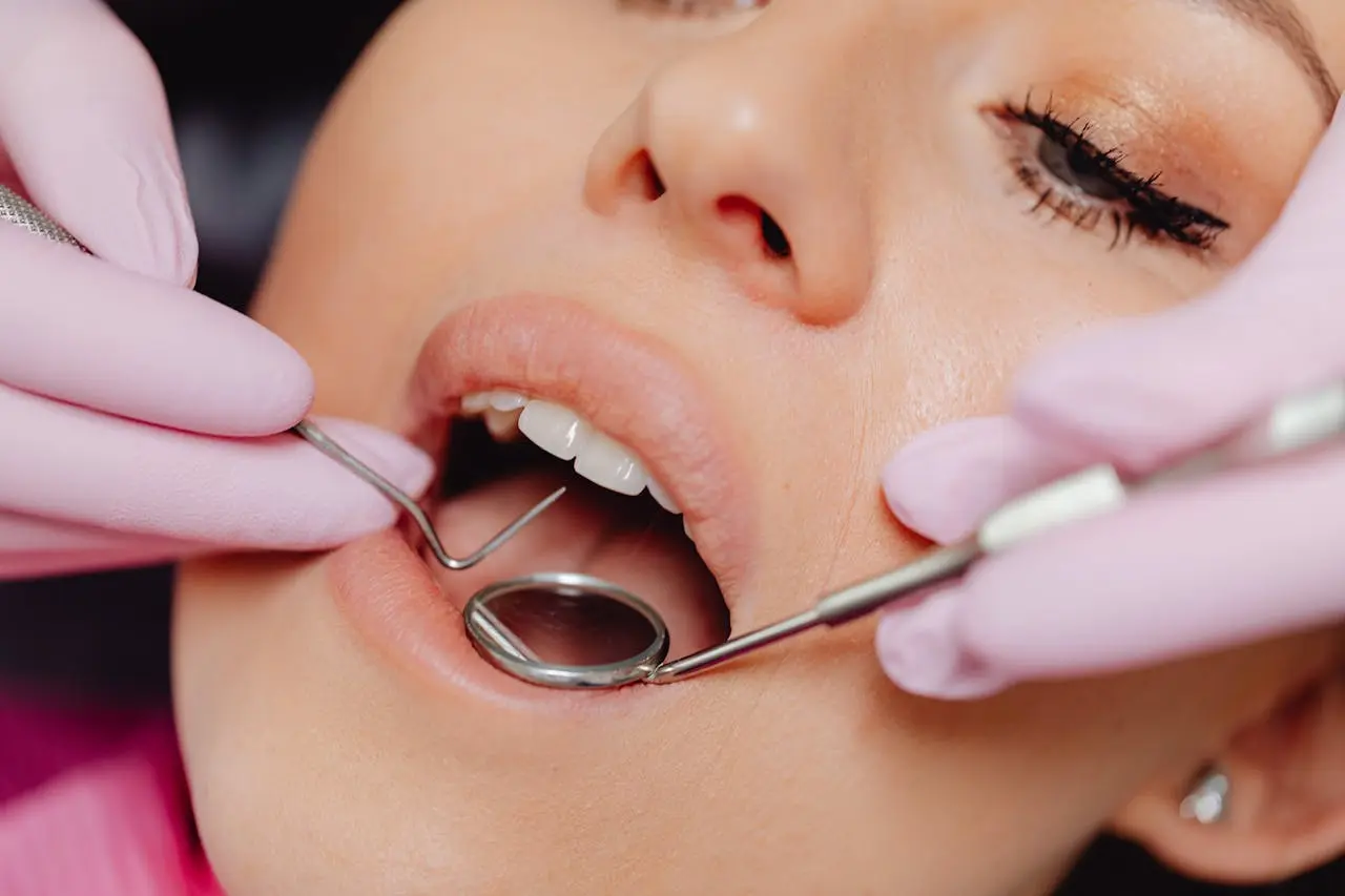 Best Orthodontics A close-up shows a patient's mouth being examined with dental tools by gloved hands. Limestone Hills Orthodontics in Austin, TX, provides thorough dental check-ups.