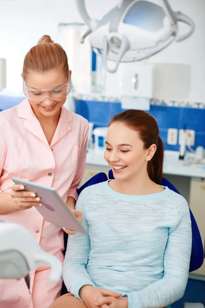 An orthodontist in Austin, TX, shows a tablet to a smiling patient in the dental chair.