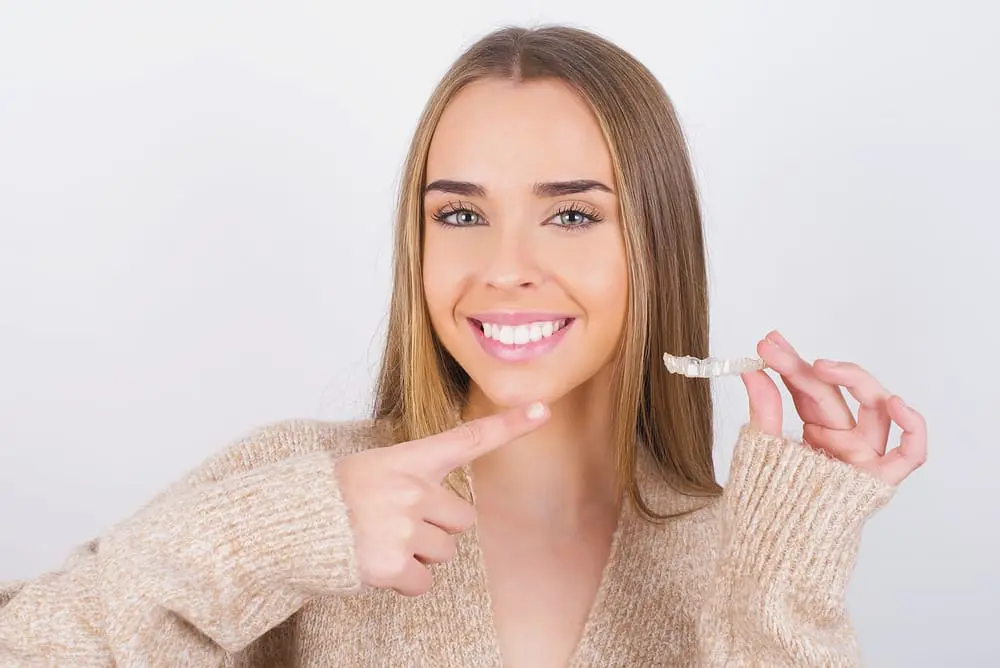 young woman holding invisalign clear aligners - How to Clean Invisalign: The Daily and Weekly Protocol | Limestone Hills Orthodontics Austin TX 