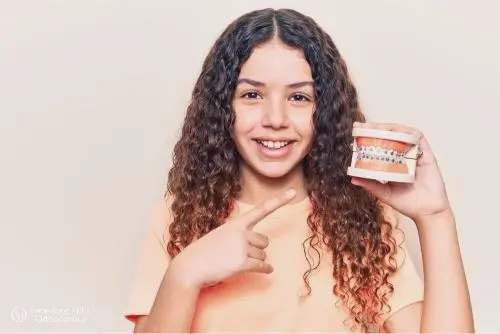 a girl pointing at teeth replica illustrating How to Floss with Braces