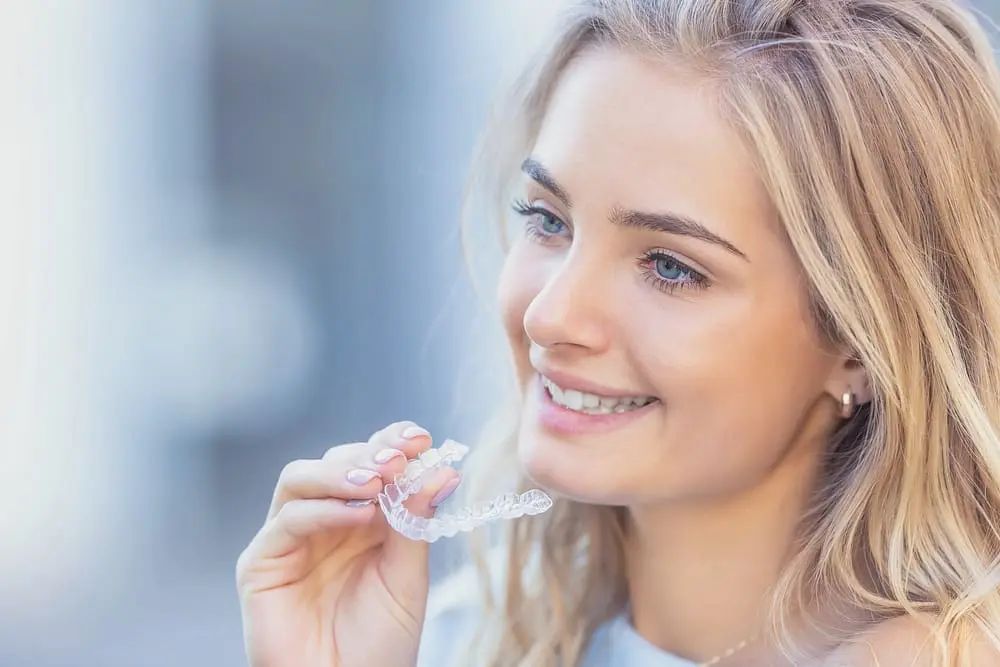 young attractive woman holding invisalign clear aligners - Byte vs Invisalign: What Austin Patients Should Know in 2026 | Limestone Hills Orthodontics