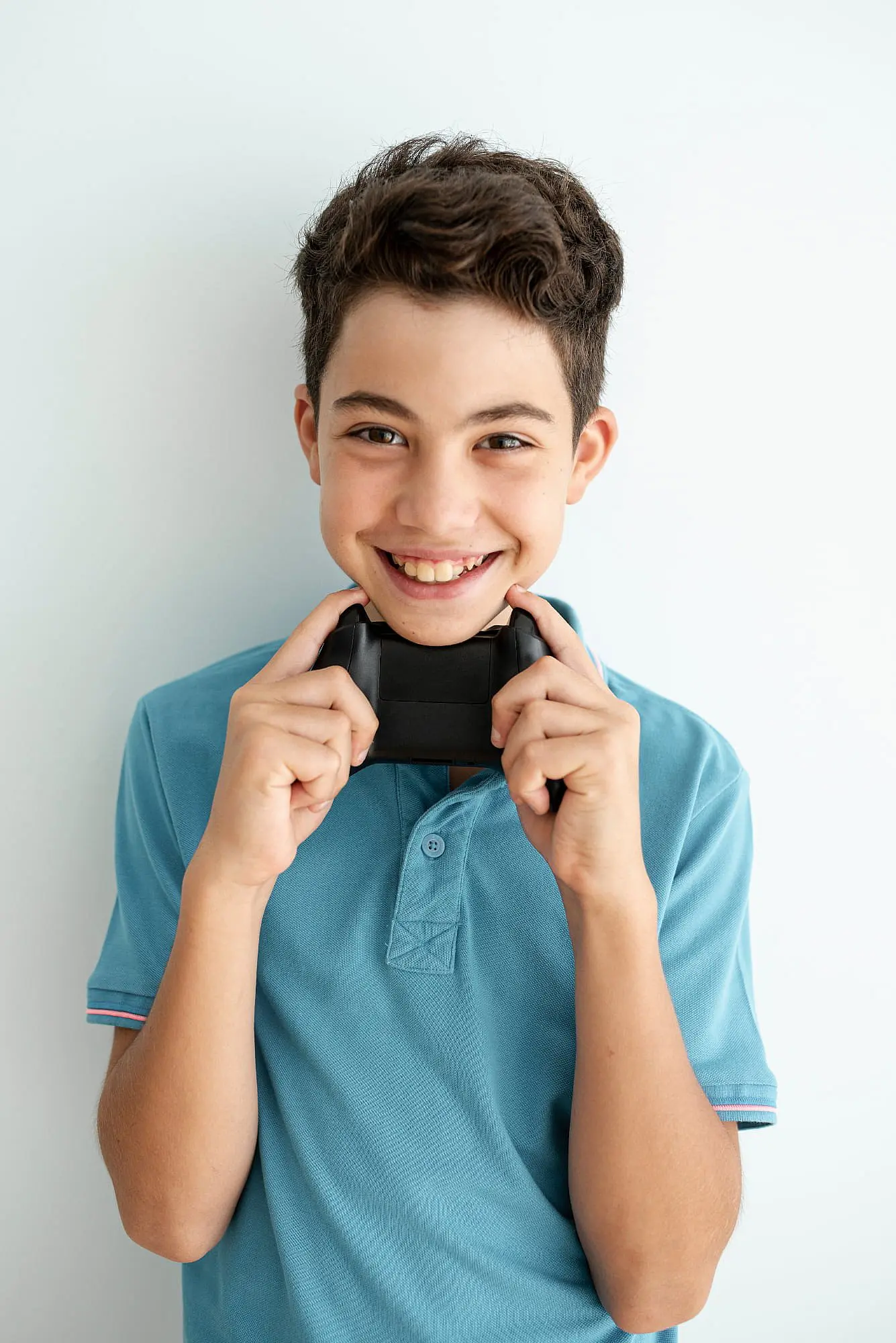 A smiling teenage boy, who appears to be of Caucasian descent based on his features and complexion, holds a video game controller. Limestone Hills Orthodontics in Austin, TX.