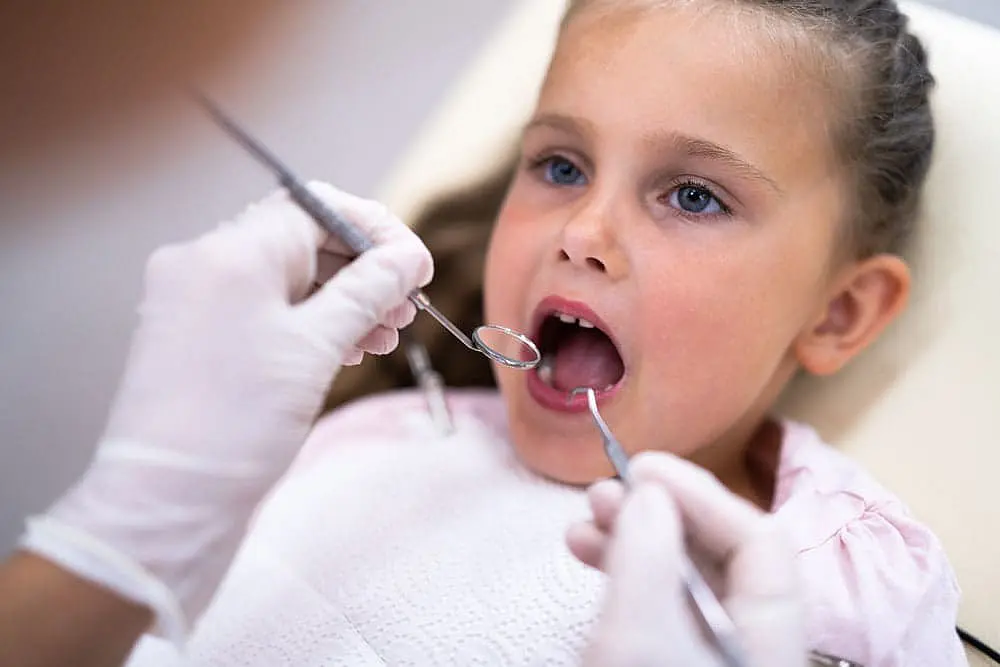 A young girl with blue eyes receives a dental check-up. Limestone Hills Orthodontics in Austin, TX, offers pediatric orthodontic care.