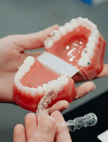 Hands hold a dental model and Invisalign aligners. Limestone Hills Orthodontics in Austin, TX, offers consultations for clear orthodontic treatment.