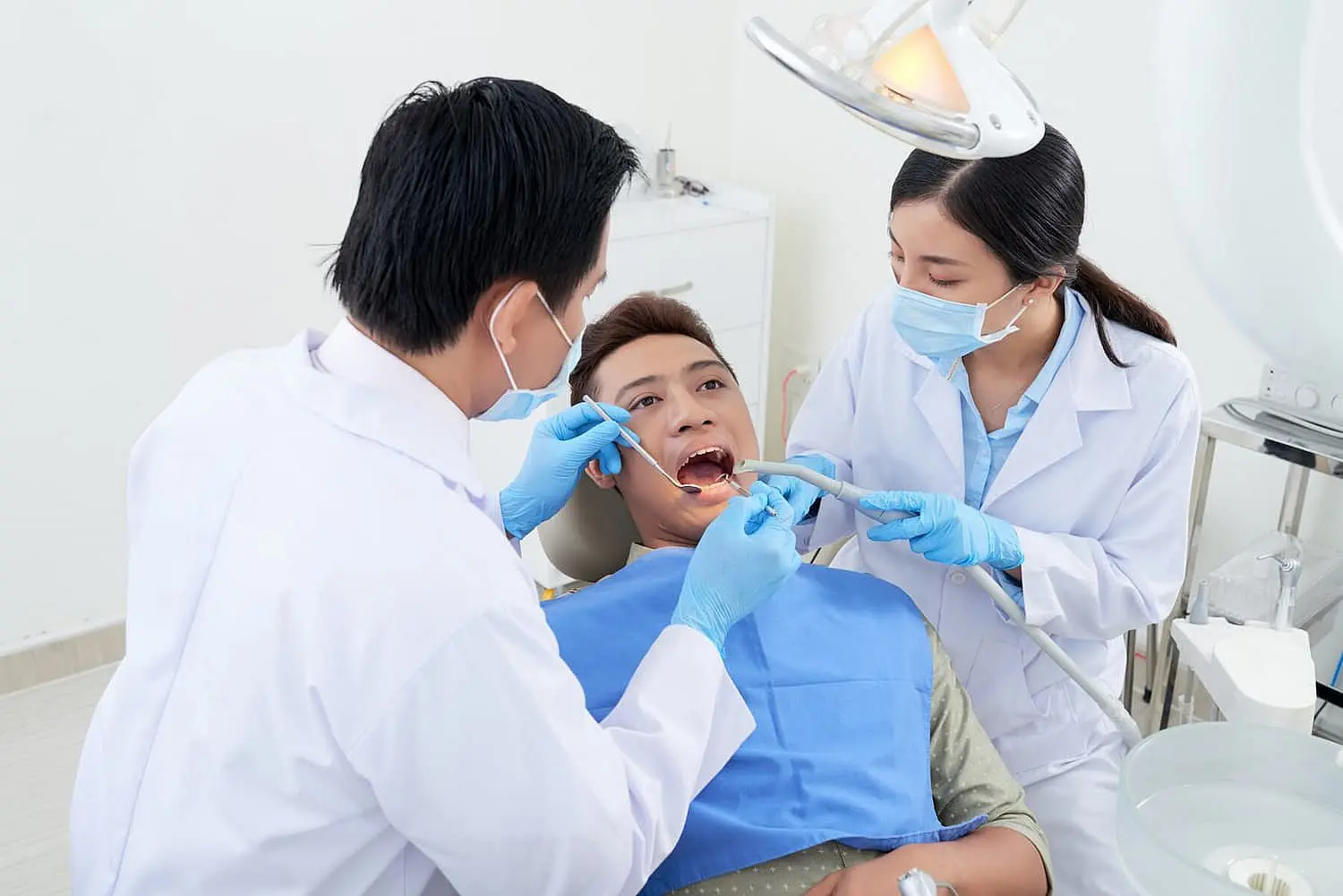 Two dental professionals, who appear to be of Asian descent based on their features, work on a patient's mouth. Limestone Hills Orthodontics in Austin, TX, provides comprehensive care.