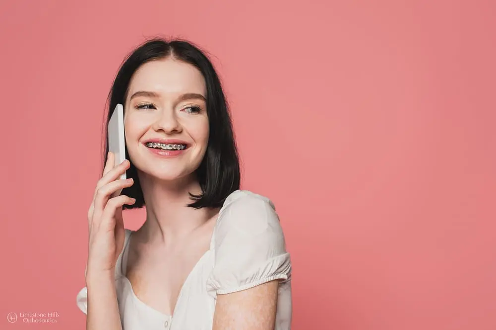 Woman with metal braces talking on her mobile phone, smiling after getting braces a second time