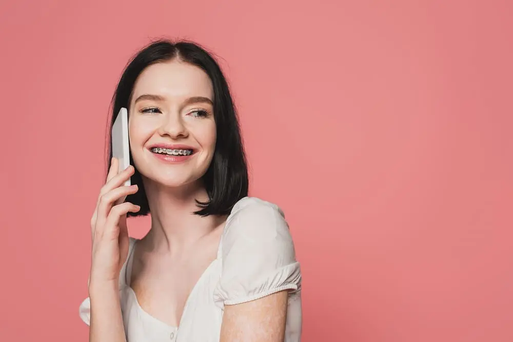 Woman with metal braces talking on her mobile phone, smiling after getting braces a second time