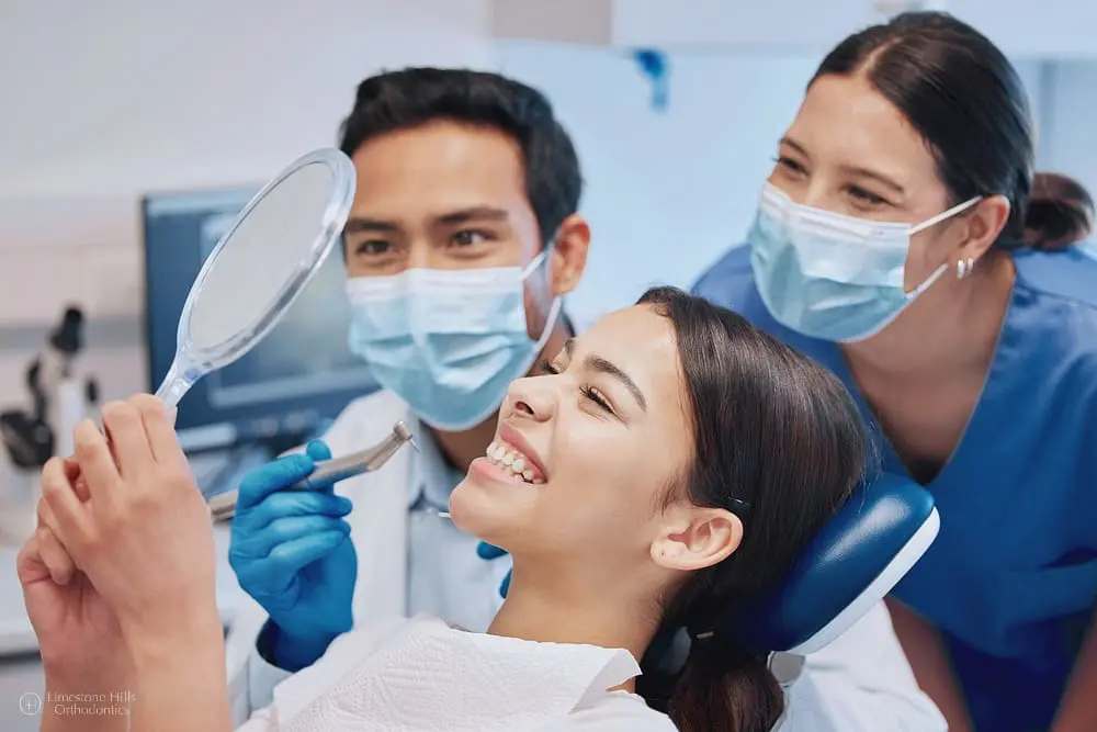 What Does an Orthodontist Do? Young patient with braces checking results in a dental mirror during an orthodontic appointment