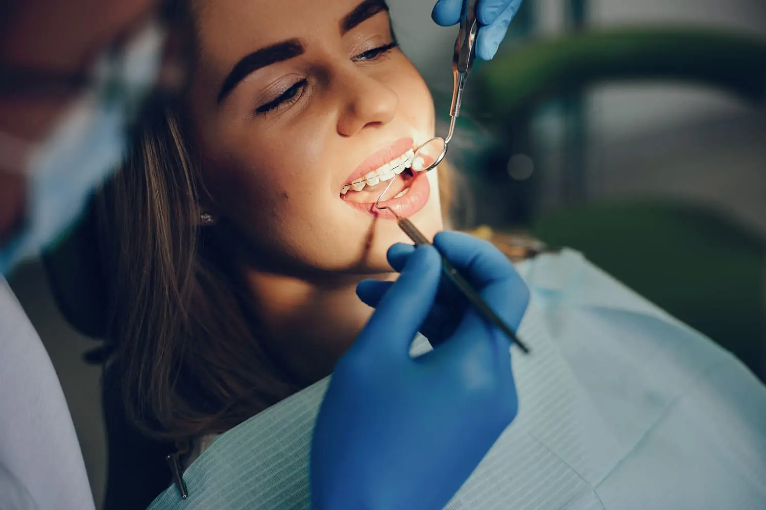A patient sits comfortably in a dental chair at Limestone Hills Orthodontics, receiving expert care from a dentist in blue gloves, precisely using tools to perfect their smile.