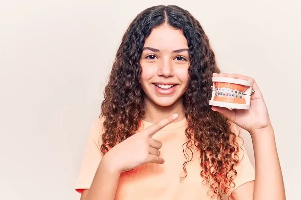 Confident young adult smiling with metal braces during an orthodontic treatment journey