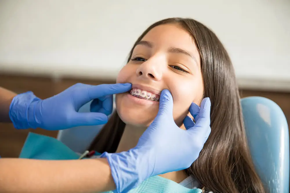 Close-up of a young adult adjusting to their new braces during their orthodontic appointment