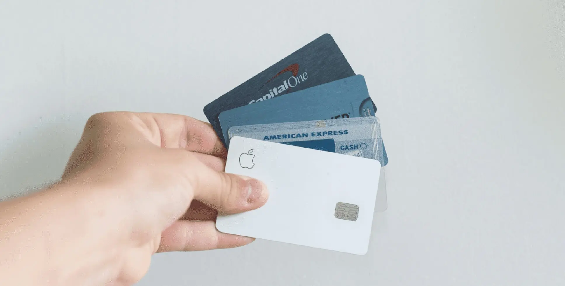 A hand holds several credit cards, including an American Express card and an Apple Card. Limestone Hills Orthodontics in Austin, TX, may accept various payment methods.