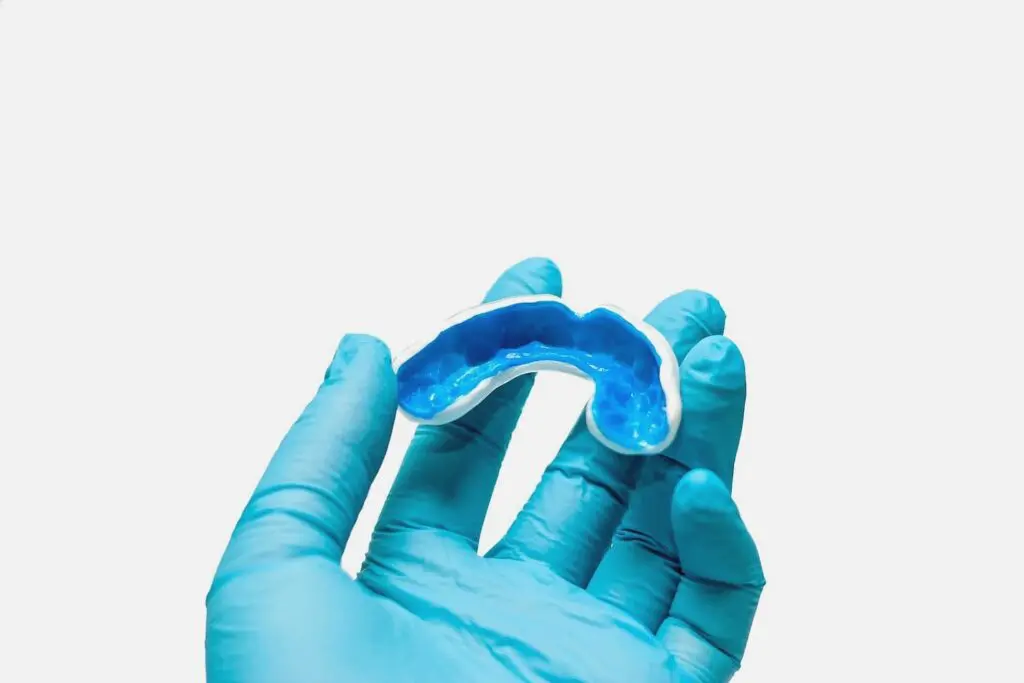 Gloved hand holding a blue orthodontic mouthguard or dental appliance as one of the dental orthotics in Austin, TX