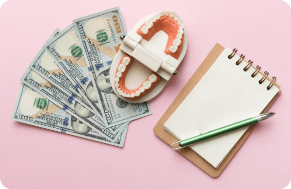 A dental model placed on US dollar bills with a notepad and pen, representing metal braces cost analysis. Limestone Hills Orthodontics in Austin, TX, provides detailed information on treatment pricing.