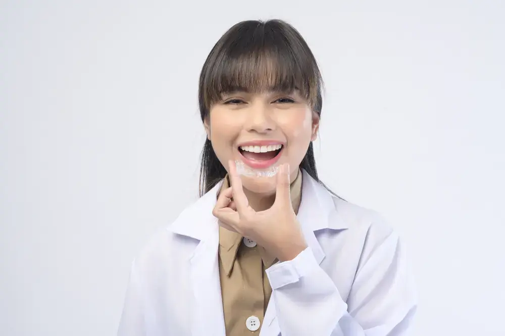 Smiling young woman pointing to clear aligners, addressing myths about clear aligner therapy. Limestone Hills Orthodontics, Austin TX.