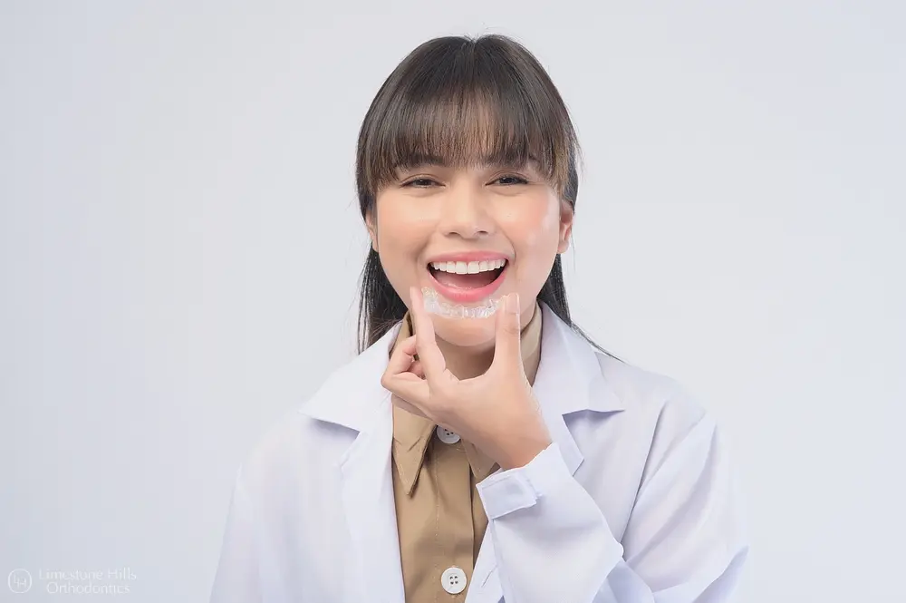young female dentist holding invisalign clear aligners white background - How Orthodontic Insurance Works in Austin, TX 