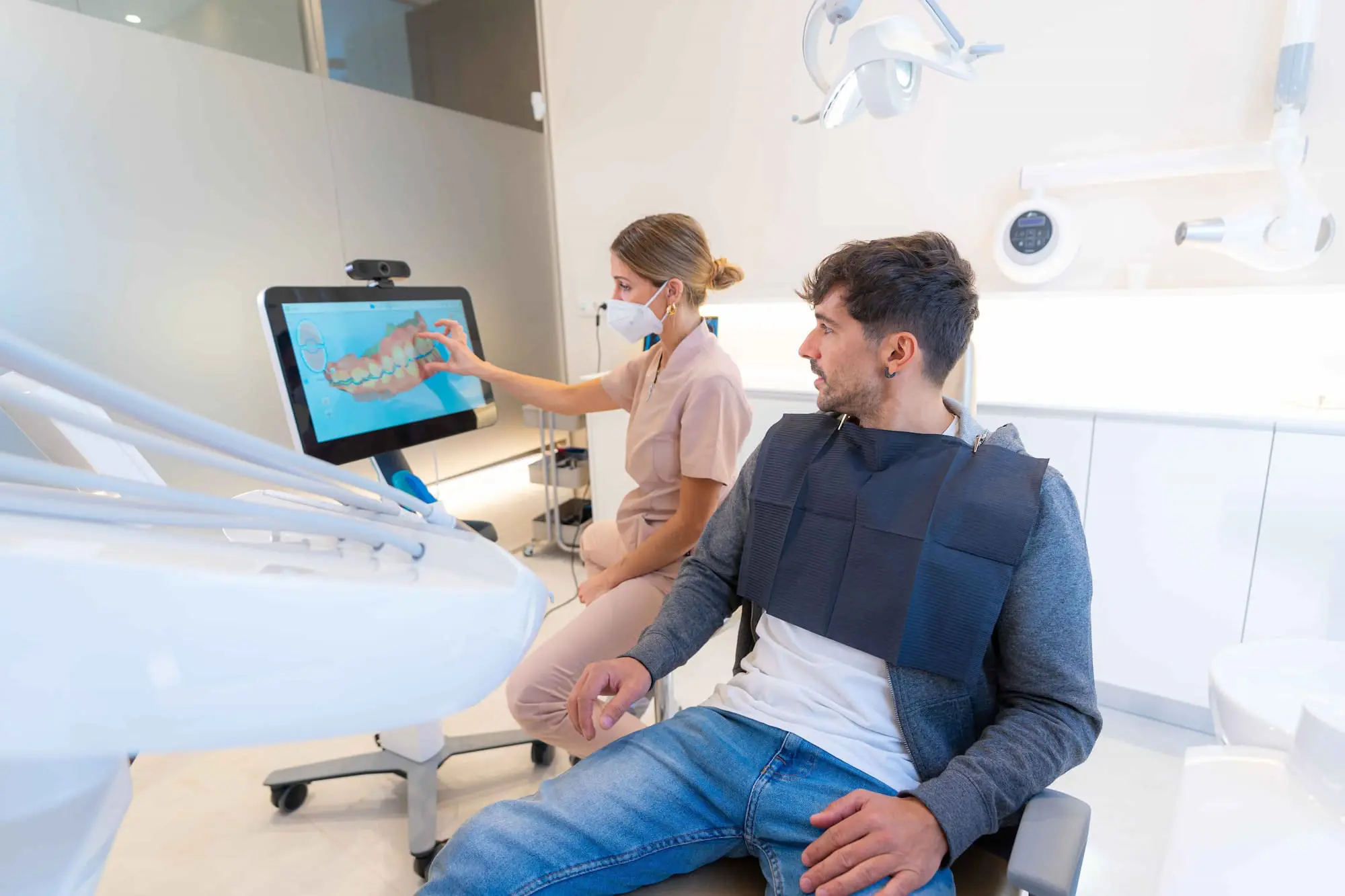 In Austin, TX, at Limestone Hills Orthodontics, a dental professional displays a 3D dental scan to a male patient on a touchscreen for Invisalign treatment.