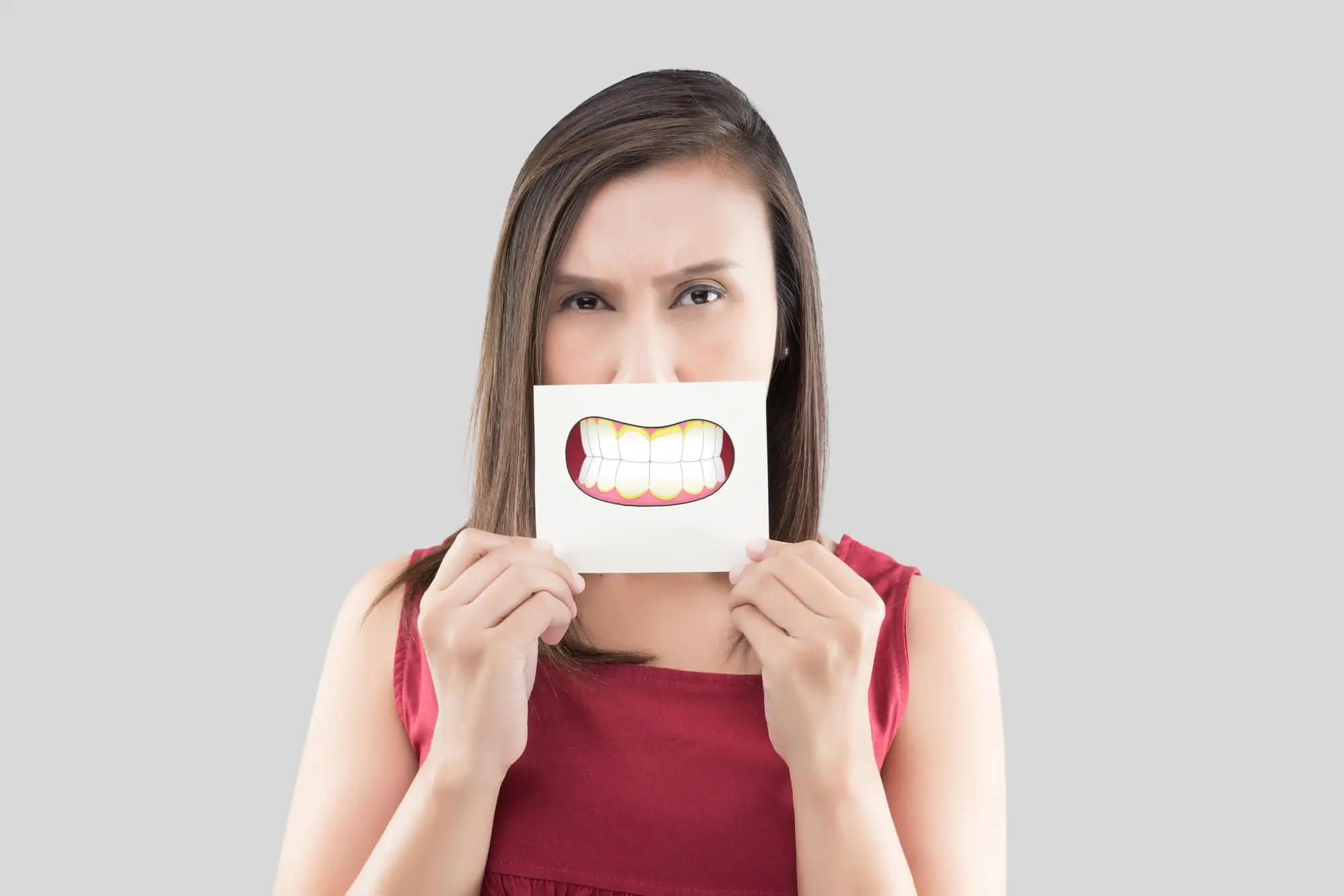 A woman holding a drawing of an underbite over her mouth, illustrating underbite correction options at Limestone Hills Orthodontics in Austin, TX.