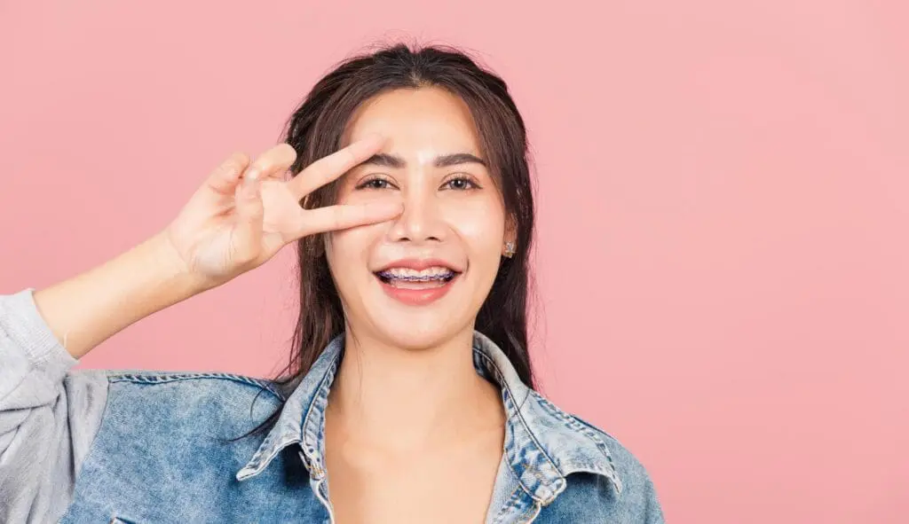 Person with colorful braces flashing a peace sign near their face, at Limestone Hills Orthodontics in Austin, TX.