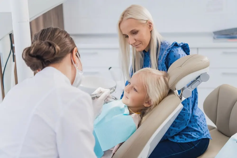 a mother watching an orthodontist taking care of her little daughter - How to Prepare Your Child for Braces: A Parent Guide | Limestone Hills Orthodontics Austin TX