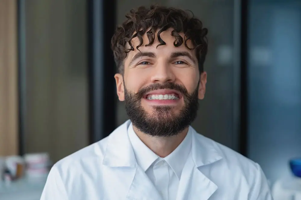 bearded man dentist clear braces showing importances dental care - Ceramic Braces vs Metal Braces: Which Should You Choose?