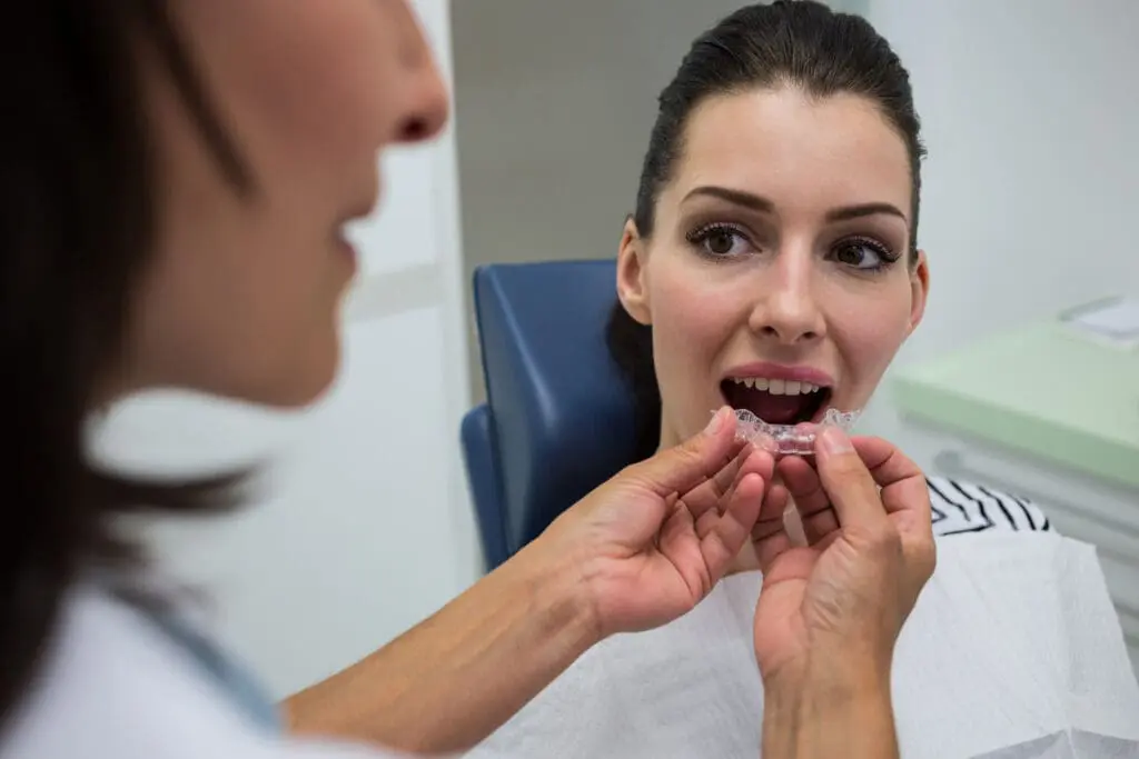 Dentist assisting a patient to wear orthodontic silicone invisible braces - Open Bite Treatment: Causes, Types, and How Orthodontics Can Help | Limestone Hills Orthodontics Austin TX
