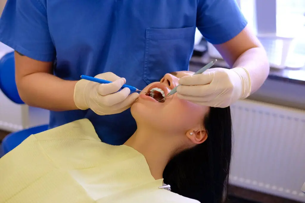 dentist hands working young woman patient with dental tools - Tongue Thrust and Orthodontic Treatment: Causes and Solutions | Limestone Hills Orthodontics Austin TX