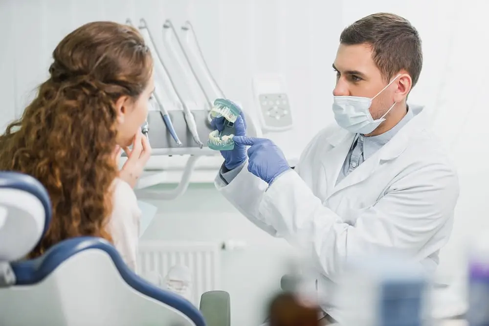 orthodontist wearing mask latex gloves pointing finger teeth model - Ozempic Teeth and Orthodontics: How GLP-1 Medications May Affect Braces Treatment | Limestone Hills Orthodontics Austin TX