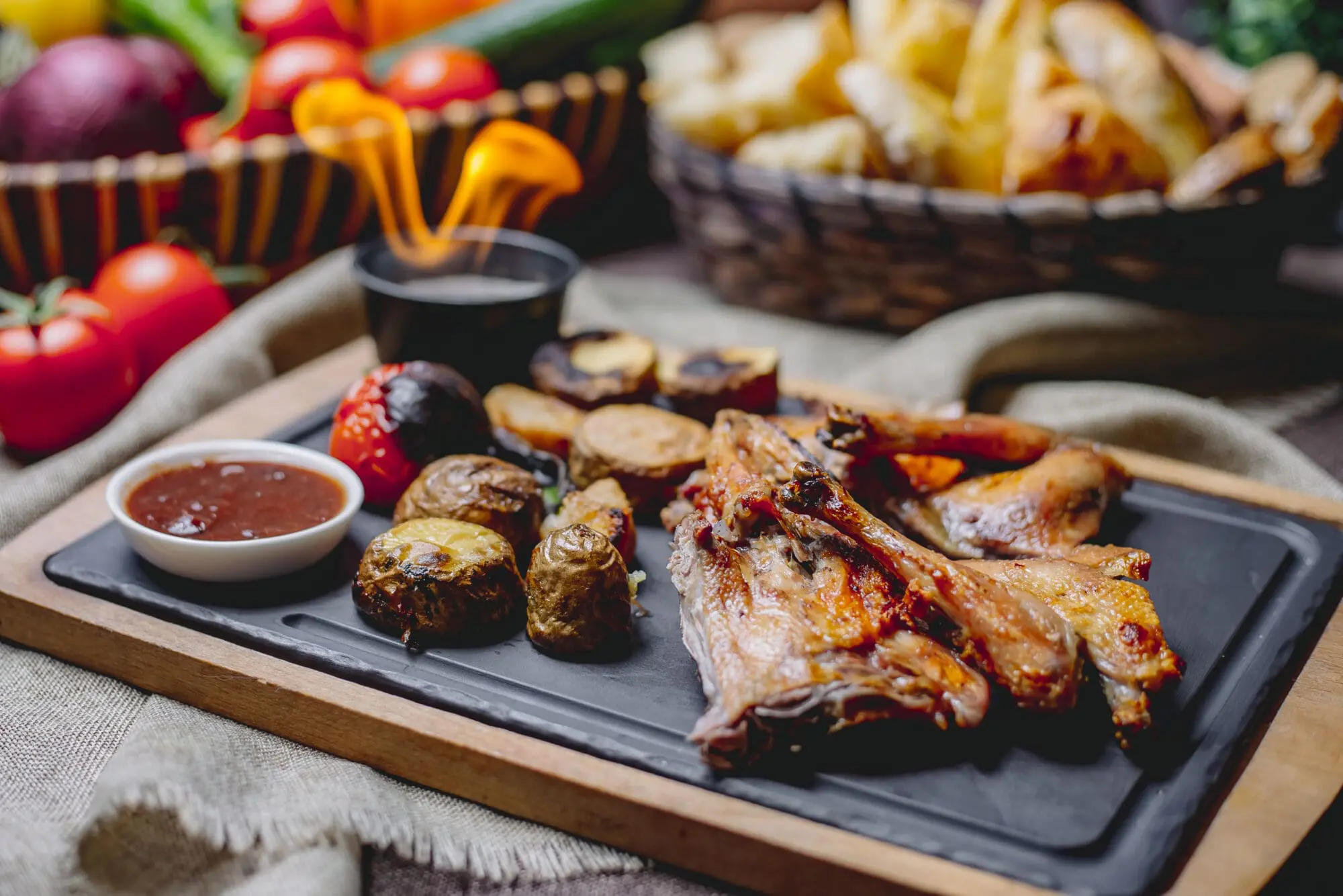 side view of roasted chicken with baked potatoes grilled vegetables and sauce on a black board - Foods to Avoid with Braces: A Practical Family Guide