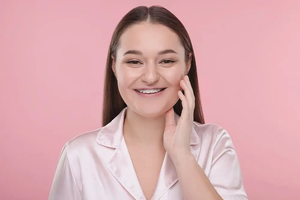 smiling woman dental metal braces pink - Am I Too Old for Braces? An Adult Orthodontics Guide | Limestone Hills Orthodontics Austin TX
