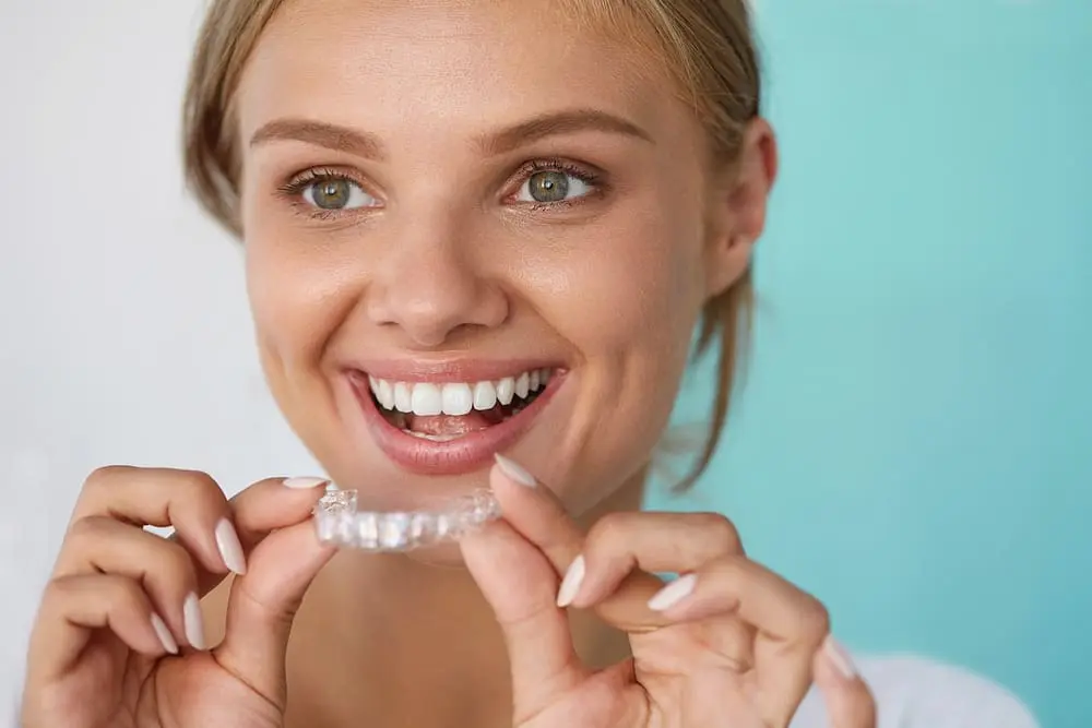 smiling woman with beautiful smile using invisalign clear aligners - How Does Invisalign Work? An Austin Orthodontist Explains the Science | Limestone Hills Orthodontics Austin TX